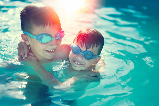 Happy little kids have fun in swimming pool graded in sunset