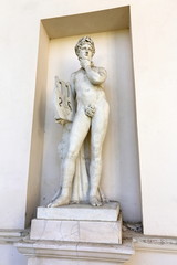 Statue of naked man holding small harp