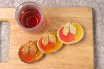 Cookies in the shape of apple with marmalade on the background of a wooden board with a drink