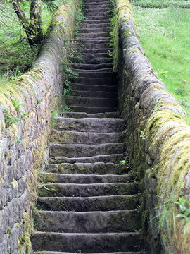 a long flight stone stairs in nature with walls and fields