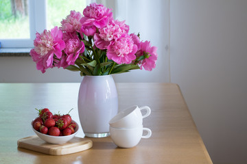 Still life from farm products. Light breakfast with fresh strawberries cottage cheese on the kitchen table. Peony flowers.