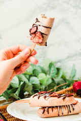 Hand holding a ice cream popsicles with chocolate and strawberries. Summer food concept.Space for text.