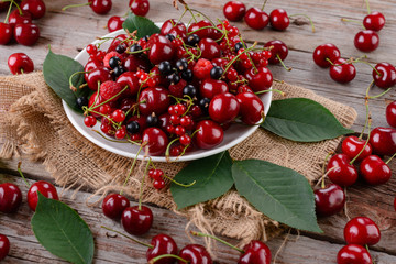 Mature cherries on a plate on a wooden table