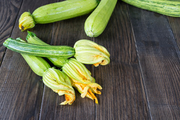 Fresh zucchini with flowers on a wooden table.