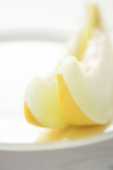 Melon cut into pieces on a white wooden table. A high key.