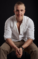 Portrait of young attractive guy in stylish outfit over dark background. 