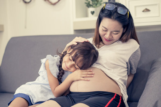 Closeup of happy child listen to belly of pregnant woman. Family having fun indoor. Mothers day concept, vintage tone