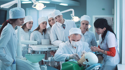 Group of students watching dentist practicing dental activity with mannequin.