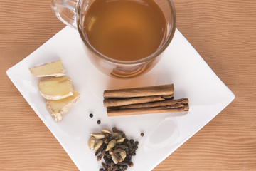 Chai tea with cinnamon, ginger and cardamom on a white plate