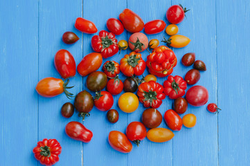 Fototapeta na wymiar Bunch of heirloom tomatoes on wooden table, top view flat lay.. Healthy eating concept