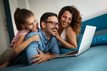 Happy family lies on bed and watching something on laptop.Laughing and fun. - obrazy, fototapety, plakaty