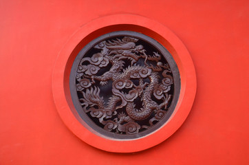 Wooden Carved dragon in circle on red background in Chinese Buddhism Temple in Lumbini, Nepal