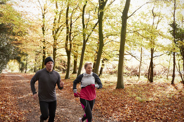 Fototapeta premium Mature Couple Running Through Autumn Woodland Together