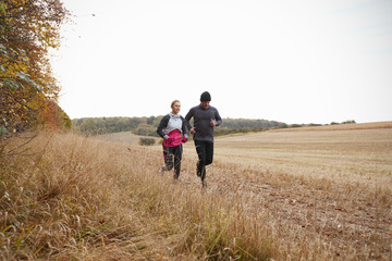 Mature Couple Running Around Autumn Field Together