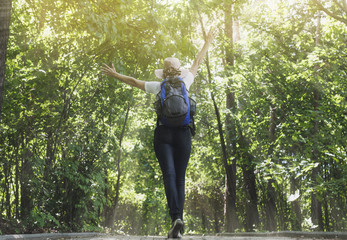 счастливая девушка с рюкзаком на прогулке в летнем лесу радуется солнцу