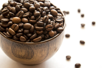 Close-up of a wooden mug of fragrant coffee beans on a white background