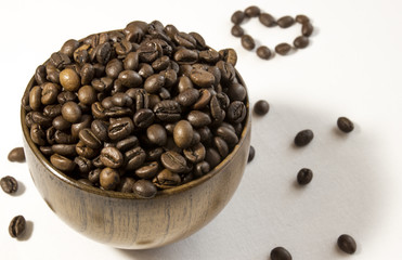 Mug of aromatic coffee beans on white background with hear