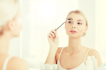 woman brushing eyebrow with brush at bathroom