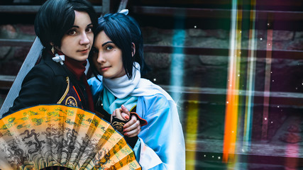 Two couples sitting on the steps and looking at the camera in front of a fan. Format 16:9 (film frame).
