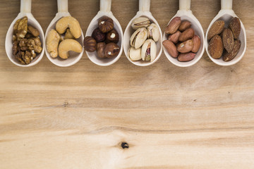 Nuts in a wooden spoons on a  wooden table.