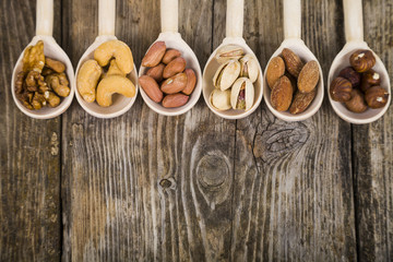 Nuts in a wooden spoons on a  wooden table.