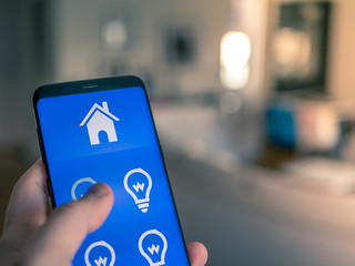 Smart home automation, mobile device with light app. Man uses his smartphone to controll the lights in the house.