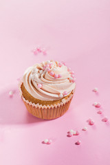 Closeup of tasty cupcakes with cream and small pearls. Pink Background.