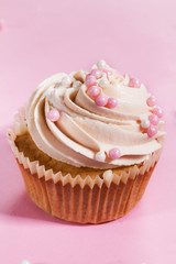 Closeup of tasty cupcakes with cream and small pearls. Pink Background.