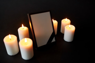Fototapeta na wymiar photo frame with black mourning ribbon and candles