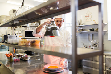 male chef heating food with lamp at  kitchen