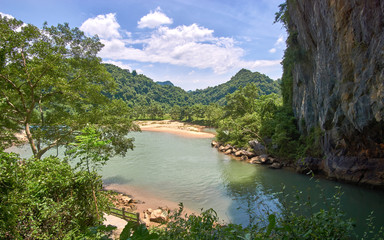 Entry to the Phong Nha Cave with clear a river into the cave and mountains in the background. Phong Nha ke bang region of Vietnam.