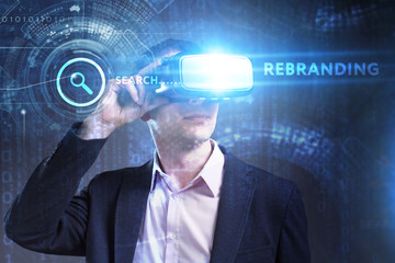 Business, Technology, Internet and network concept. Young businessman working in virtual reality glasses sees the inscription: Rebranding