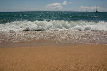 Clean sandy beach, azure Mediterranean sea, sailboat on the horizon
