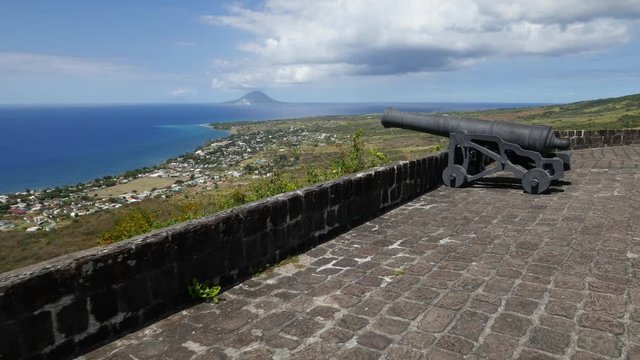 Reverse tracking shot of the cannons facing the ocean and Nevis at the Brimstone Hill Fortress National Park in St. Kitts, West Indies