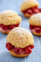 Eclairs with mascarpone cream and raspberries.
