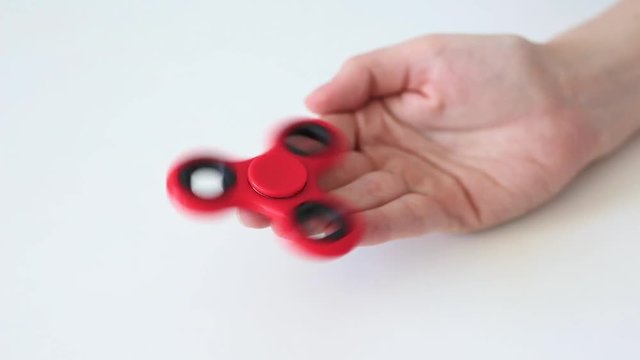 close up of fidget spinner rotating on female hand over white