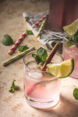 Summer refreshing drink, cocktail. Homemade organic mojito or lemonade with rhubarb, mint and lime. On a light stone table, in glasses and a bottle. Copy space