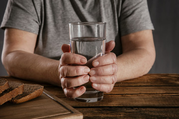 Elderly woman holding glass of water on table. Poverty concept