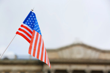 Waving USA flag and blurred building on background