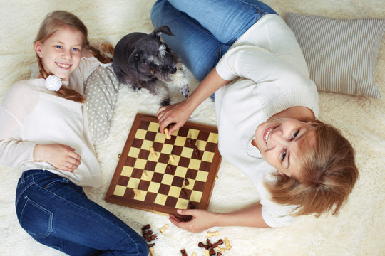 Mother and child are playing chess while spending time together at home. View from above