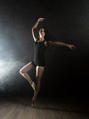 Fototapeta premium young beautiful ballet dancer in pointe shoes, dancing in a smoke on a dark background.