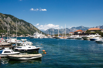 Fototapeta na wymiar Kotor bay ships and boats in marina with beautiful mountain landscape in background.