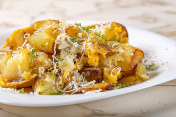 Fried potatoes with scrambled eggs and parmesan cheese on plate
