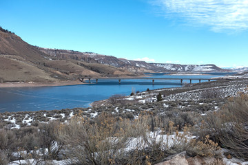 Obraz premium Bridge Crossing Over Frozen Gunnison River Sunny Cold Winter Day