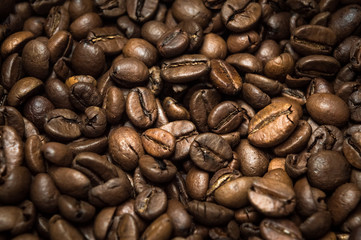 Closeup of coffee beans scattered randomly. Beautiful brown texture.