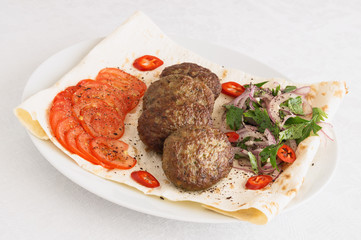 meatballs with sliced tomatoes, chili, and salad of red onion, parsley, and garlic sprinkled with sumac and black pepper 