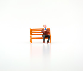 Miniature business man sitting on wooden chair