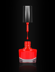  Red nail polish dripping from brush into bottle on black background