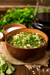 Okroshka. Traditional Russian summer cold soup with sausage, vegetables and kvass in bowl on wooden background.