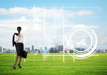 Camera headed woman standing on green grass against modern cityscape